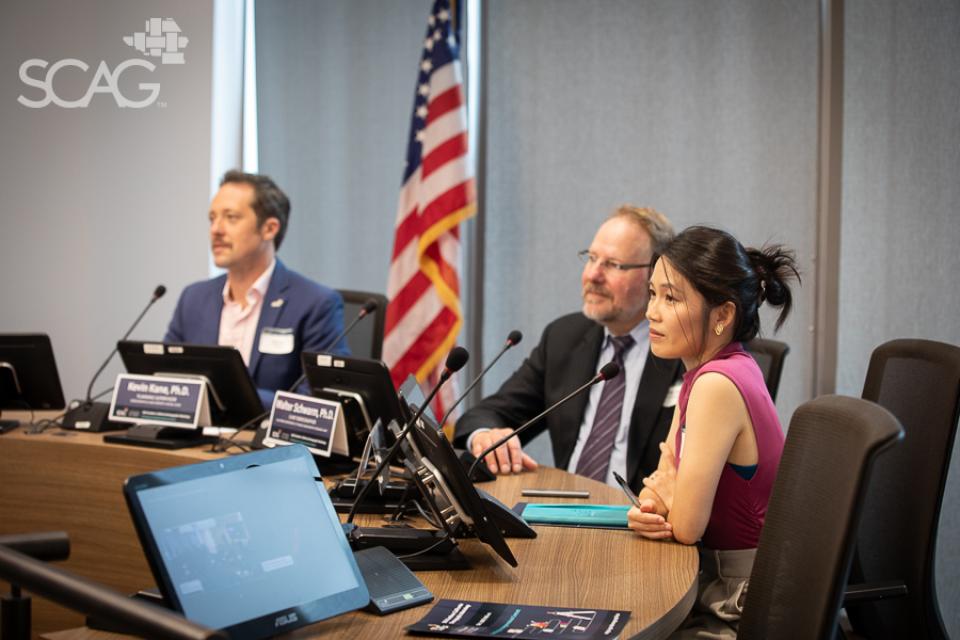 Panelists at a conference table with an American flag in the background.