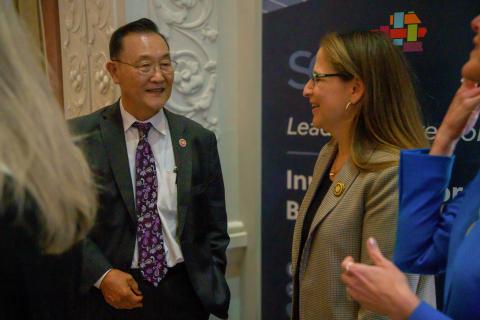 Smiling people in business attire having a conversation at an event.